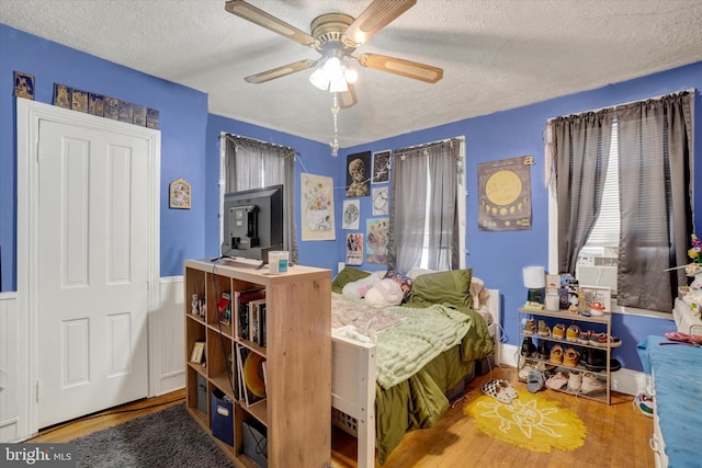 216 Hanover St, Glen Rock, PA 17327 - bedroom with a textured ceiling, wood finished floors, cooling unit, ceiling fan, and wainscoting