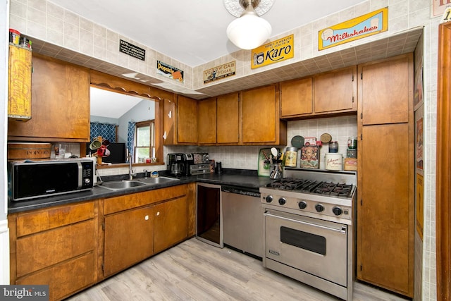 26 Worrell Rd, Tabernacle, NJ 08088 - kitchen with appliances with stainless steel finishes, brown cabinetry, dark countertops, light wood-style floors, and tasteful backsplash