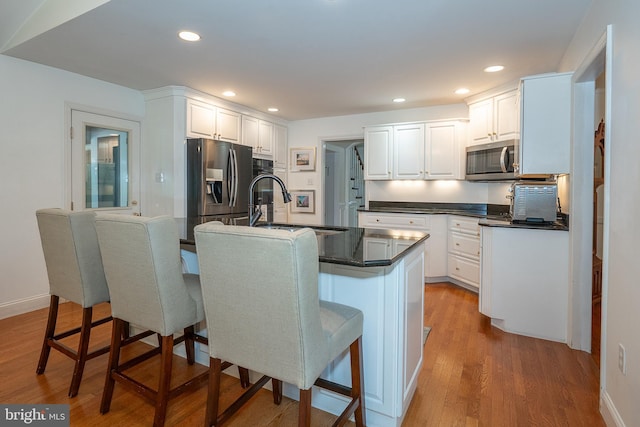 406 Devon State Rd, Devon, PA 19333 - kitchen with appliances with stainless steel finishes, dark countertops, white cabinets, light wood finished floors, and a breakfast bar
