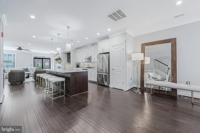 43561 Michigan Sq, Leesburg, VA 20176 - kitchen featuring appliances with stainless steel finishes, open floor plan, light countertops, white cabinetry, and a kitchen breakfast bar