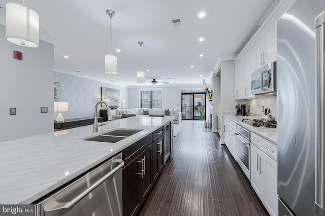 43561 Michigan Sq, Leesburg, VA 20176 - kitchen featuring stainless steel appliances, ornamental molding, open floor plan, light stone countertops, and white cabinets