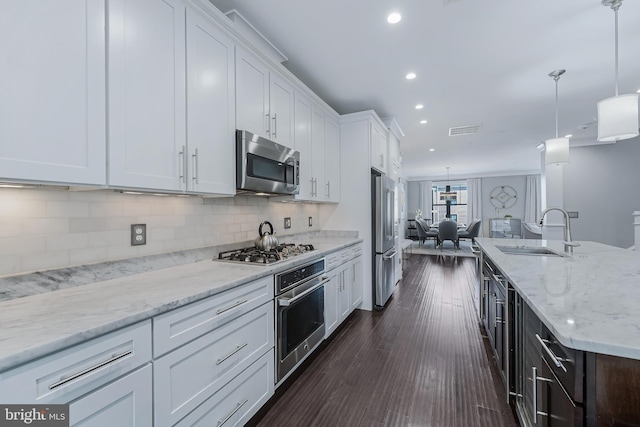 43561 Michigan Sq, Leesburg, VA 20176 - kitchen with stainless steel appliances, white cabinetry, backsplash, hanging light fixtures, and recessed lighting