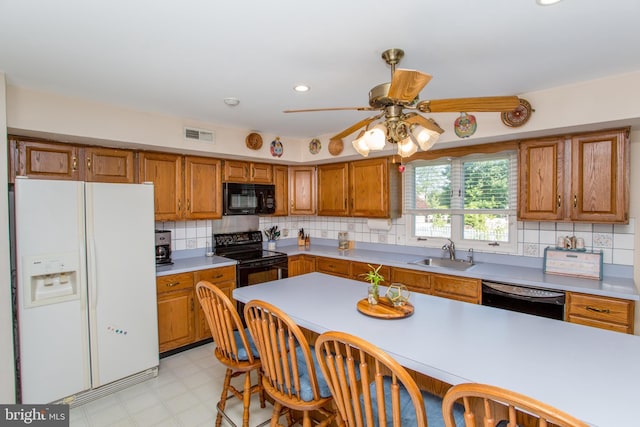 105 Wood Dr, Southampton, PA 18966 - kitchen with black appliances, brown cabinets, a kitchen breakfast bar, decorative backsplash, and light countertops