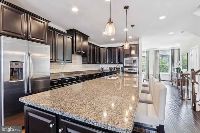 221 Patriots Path, Malvern, PA 19355 - kitchen featuring appliances with stainless steel finishes, decorative backsplash, a spacious island, a breakfast bar area, and light stone counters