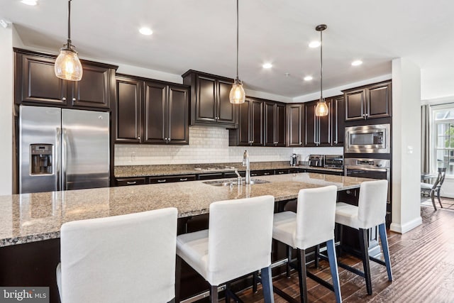 221 Patriots Path, Malvern, PA 19355 - kitchen with appliances with stainless steel finishes, tasteful backsplash, dark wood finished floors, light stone counters, and dark brown cabinets