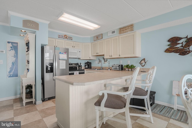 427 14th St Unit 10203, Ocean City, MD 21842 - kitchen with appliances with stainless steel finishes, a peninsula, cream cabinets, a kitchen bar, and light countertops