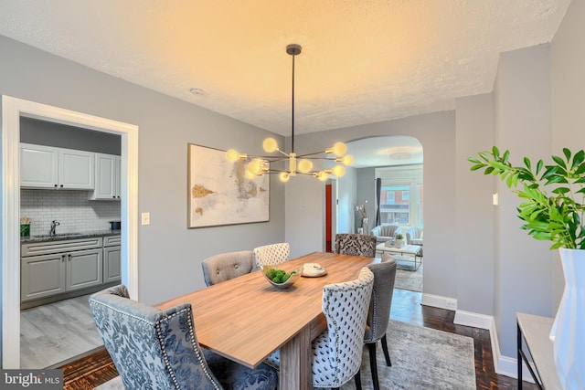 4316 Shamrock Ave, Baltimore, MD 21206 - dining space featuring arched walkways, wood finished floors, and a chandelier