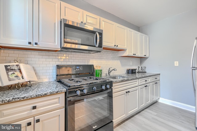 4316 Shamrock Ave, Baltimore, MD 21206 - kitchen with appliances with stainless steel finishes, light wood-type flooring, light stone counters, and backsplash