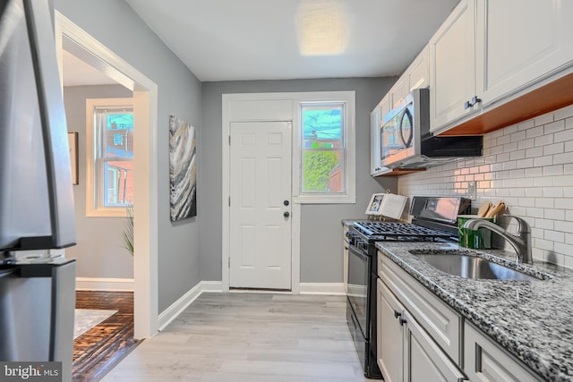 4316 Shamrock Ave, Baltimore, MD 21206 - kitchen featuring gas stove, stainless steel microwave, stone counters, decorative backsplash, and light wood-style floors