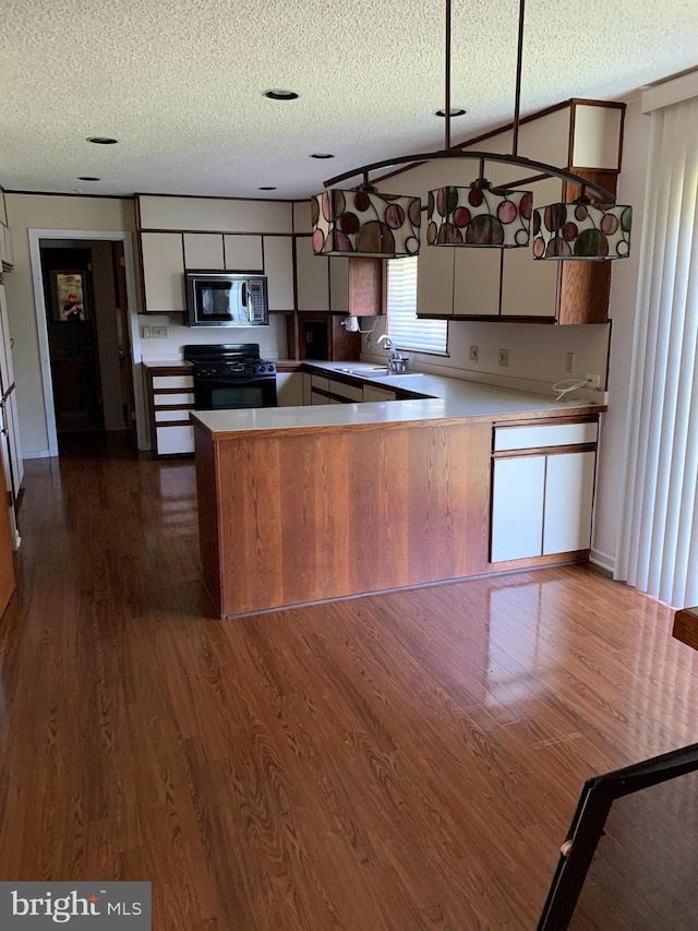 70 Hargrave Ln, Media, PA 19063 - kitchen featuring black appliances, a textured ceiling, dark wood-style floors, a peninsula, and light countertops