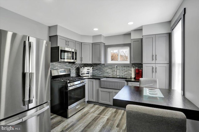 553 Wunder St Fl 1St, Reading, PA 19602 - kitchen featuring stainless steel appliances, gray cabinets, dark countertops, tasteful backsplash, and light wood-style floors