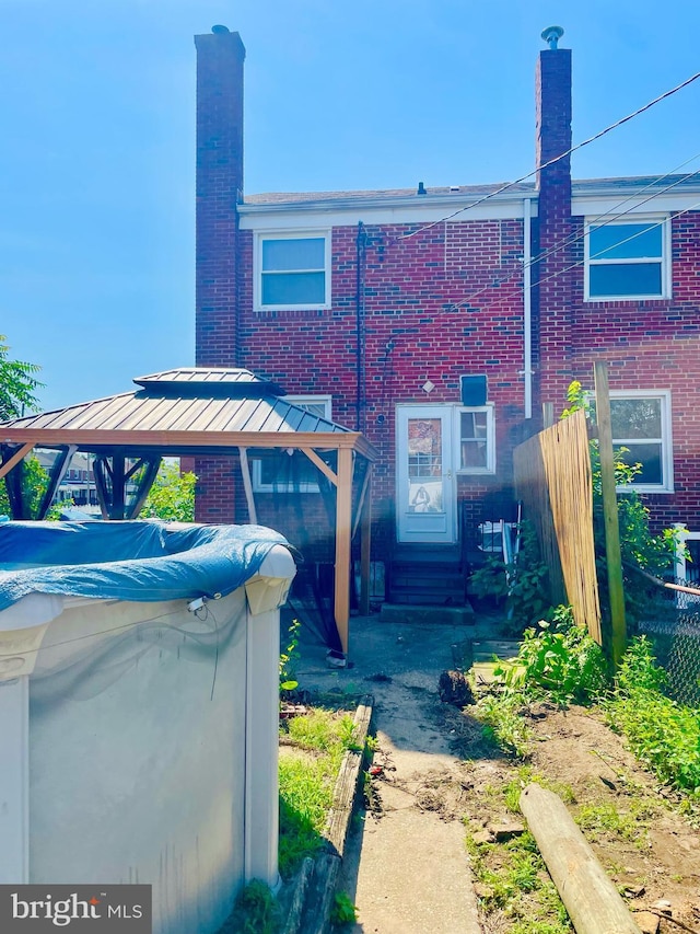 1902 Kelmore Rd, Baltimore, MD 21222 - back of property featuring a chimney, brick siding, a gazebo, and entry steps