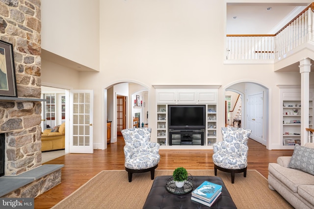 211 Twinings Ln, Wayne, PA 19087 - living area with arched walkways, wood finished floors, stairs, a high ceiling, and built in features