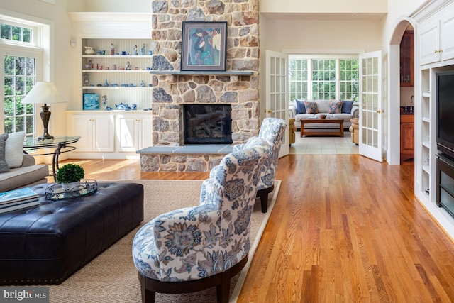211 Twinings Ln, Wayne, PA 19087 - living area with light wood finished floors, a stone fireplace, built in features, and arched walkways