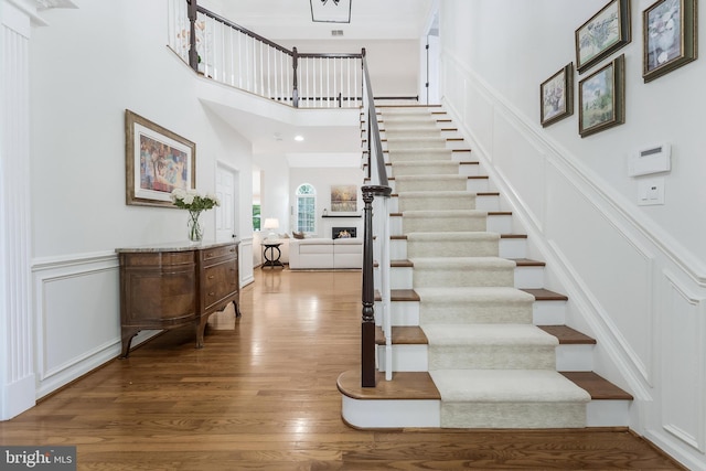 12801 Owlsley Way, Herndon, VA 20171 - stairs featuring a decorative wall, wood finished floors, a wainscoted wall, and a towering ceiling