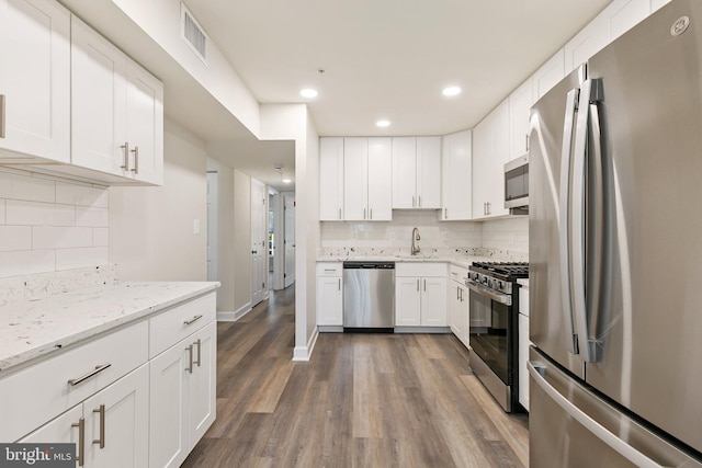 826 Quince Orchard Blvd Unit 101, Gaithersburg, MD 20878 - kitchen featuring stainless steel appliances, backsplash, dark wood-style flooring, white cabinets, and light stone counters