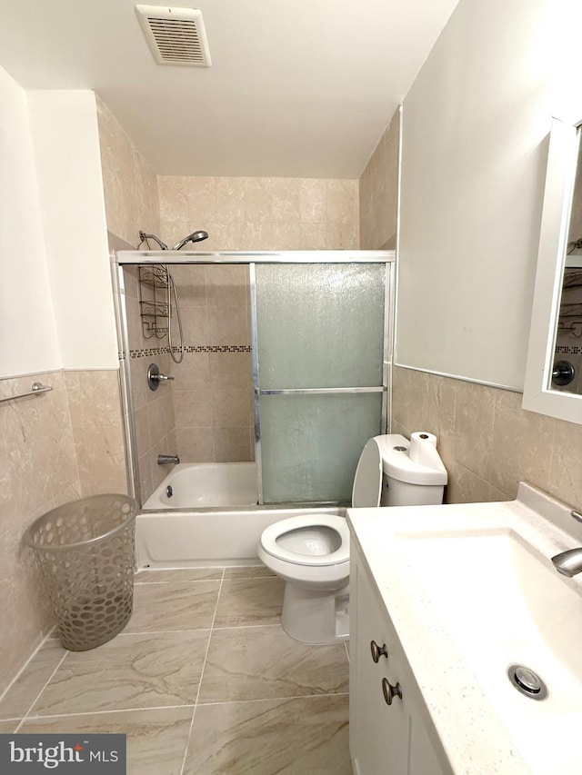 1611 S 28th St, Philadelphia, PA 19145 - full bath featuring tile walls, vanity, bath / shower combo with glass door, a wainscoted wall, and marble finish flooring