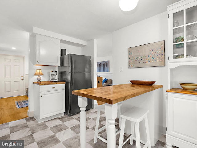 285 Laguna Cir, Severna Park, MD 21146 - kitchen with butcher block counters, freestanding refrigerator, white cabinets, glass insert cabinets, and a breakfast bar area