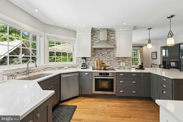 2109 Main St, Bethlehem, PA 18017 - kitchen with appliances with stainless steel finishes, wall chimney range hood, light countertops, a peninsula, and white cabinets