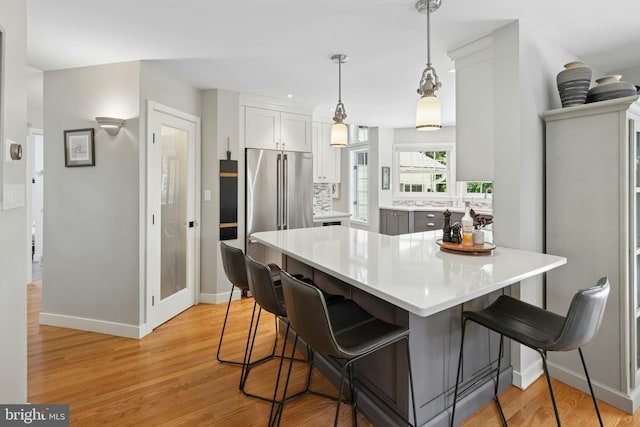 2109 Main St, Bethlehem, PA 18017 - kitchen featuring a breakfast bar area, light countertops, light wood-type flooring, white cabinets, and decorative light fixtures