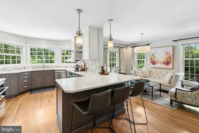 2109 Main St, Bethlehem, PA 18017 - kitchen featuring gray cabinetry, a peninsula, light countertops, a kitchen breakfast bar, and light wood-type flooring