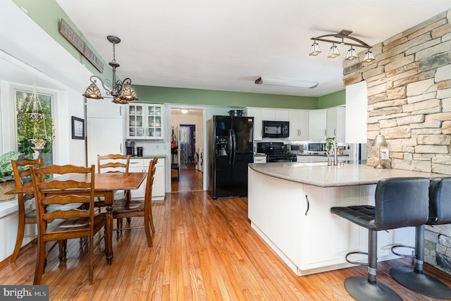 21 Black Bass, Fairfield, PA 17320 - kitchen featuring black appliances, a peninsula, light wood-style floors, white cabinets, and glass insert cabinets