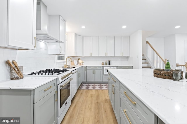 341 Ashford Dr, Lancaster, PA 17601 - kitchen featuring white appliances, wall chimney range hood, gray cabinetry, light wood-style floors, and decorative backsplash
