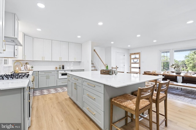 341 Ashford Dr, Lancaster, PA 17601 - kitchen with gray cabinets, a breakfast bar area, light wood-style floors, recessed lighting, and decorative backsplash