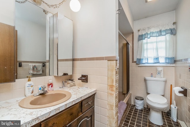 2057 Grove St, Allentown, PA 18104 - bathroom with tile walls, vanity, tile patterned flooring, wainscoting, and bath / shower combo with glass door