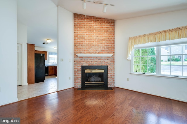 3217 Garfield Ave, Reading, PA 19605 - unfurnished living room featuring lofted ceiling, light wood-style flooring, a fireplace, plenty of natural light, and track lighting