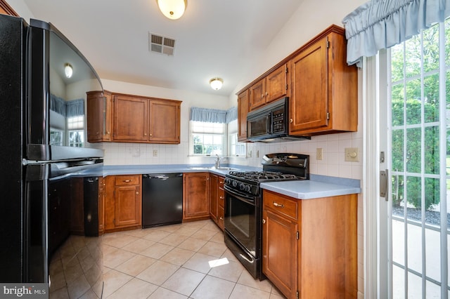 3217 Garfield Ave, Reading, PA 19605 - kitchen with black appliances, brown cabinetry, tasteful backsplash, light countertops, and light tile patterned floors