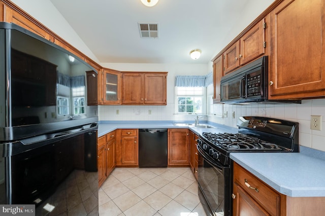 3217 Garfield Ave, Reading, PA 19605 - kitchen with black appliances, brown cabinetry, decorative backsplash, light tile patterned floors, and light countertops