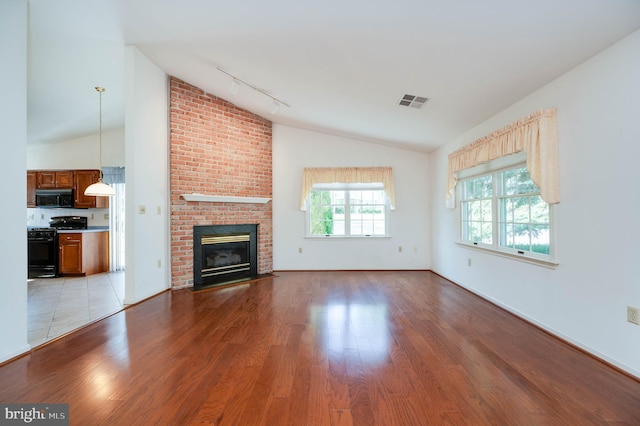 3217 Garfield Ave, Reading, PA 19605 - unfurnished living room featuring vaulted ceiling, light wood finished floors, rail lighting, and a fireplace