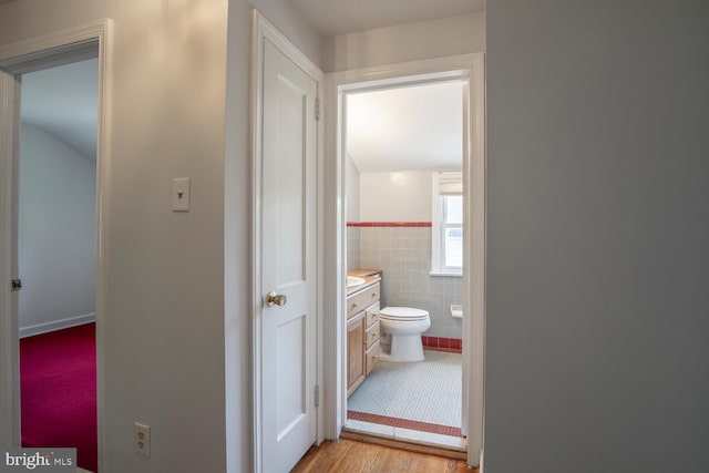 56 Meadowbrook Ave, Hatboro, PA 19040 - hallway featuring tile walls, lofted ceiling, light wood-style floors, and wainscoting
