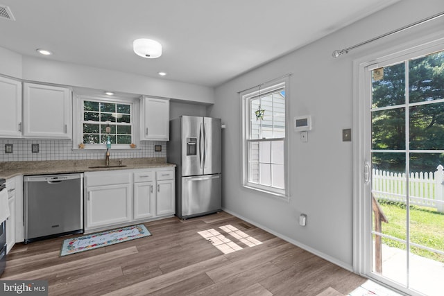 31 Violet Ln, Newtown, PA 18940 - kitchen with appliances with stainless steel finishes, backsplash, white cabinetry, light wood finished floors, and light stone counters