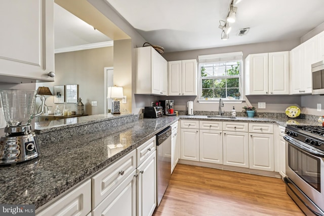 45050 Brae Ter Unit 101, Ashburn, VA 20147 - kitchen with appliances with stainless steel finishes, white cabinetry, light wood finished floors, dark stone countertops, and crown molding