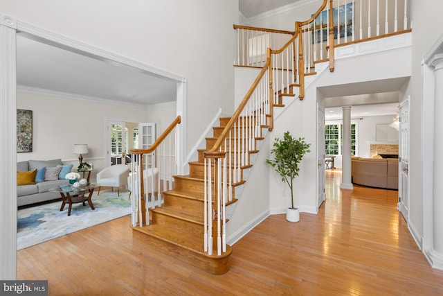 7 Shady Brook Ln, Cranbury, NJ 08512 - staircase featuring wood finished floors, a fireplace, a high ceiling, crown molding, and decorative columns