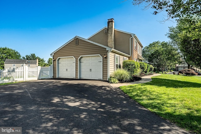 2107 Carol Ln, East Norriton, PA 19401 - view of side of property featuring a chimney, driveway, an attached garage, and a gate