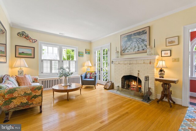 304 Summers Dr, Alexandria, VA 22301 - living room featuring wood-type flooring, a brick fireplace, ornamental molding, and radiator