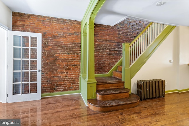 1148 S 12th St, Philadelphia, PA 19147 - stairs featuring radiator heating unit, wood finished floors, and brick wall