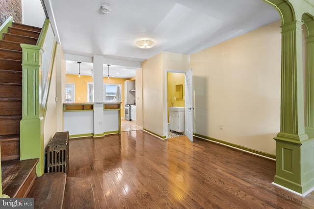 1148 S 12th St, Philadelphia, PA 19147 - unfurnished living room with radiator, stairway, hardwood / wood-style floors, ornate columns, and arched walkways