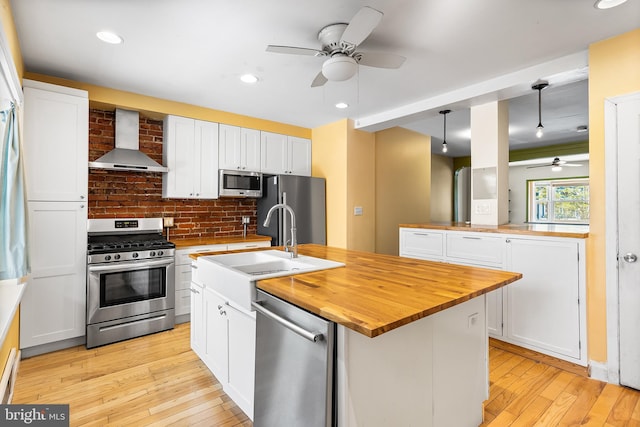 1148 S 12th St, Philadelphia, PA 19147 - kitchen featuring stainless steel appliances, wall chimney exhaust hood, ceiling fan, butcher block counters, and tasteful backsplash