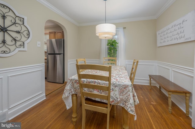 416 Copley Rd, Haddonfield, NJ 08033 - dining area featuring crown molding, light wood finished floors, arched walkways, a decorative wall, and a wainscoted wall