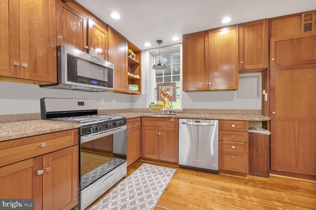 7901 Warfield Rd, Gaithersburg, MD 20882 - kitchen with stainless steel appliances, brown cabinets, light wood-style flooring, backsplash, and recessed lighting