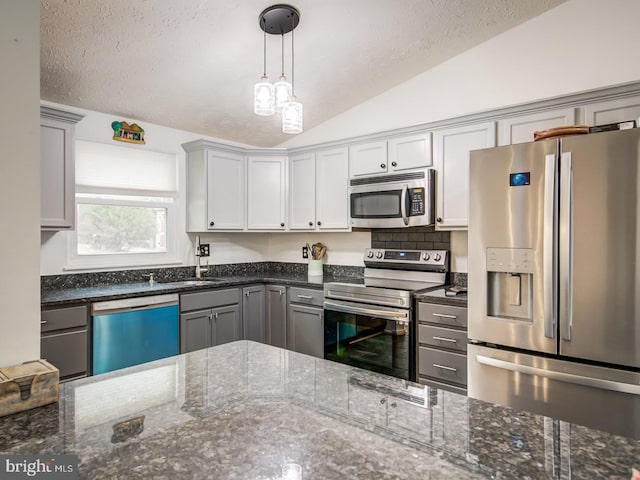 9907 Treetop Ln, Lanham, MD 20706 - kitchen featuring appliances with stainless steel finishes, lofted ceiling, gray cabinets, hanging light fixtures, and dark stone countertops