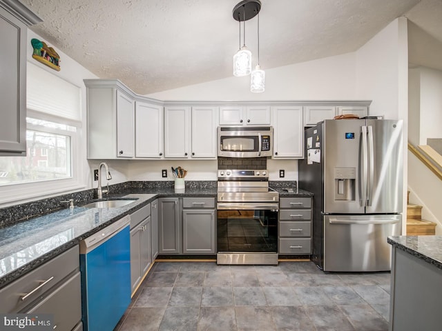 9907 Treetop Ln, Lanham, MD 20706 - kitchen featuring stainless steel appliances, lofted ceiling, gray cabinets, dark stone countertops, and decorative light fixtures