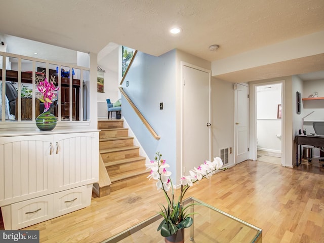 9907 Treetop Ln, Lanham, MD 20706 - stairs with wood finished floors, a textured ceiling, and recessed lighting