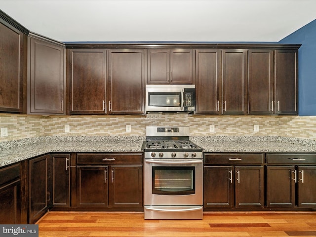 12404 Carriage Park Pl, Clarksburg, MD 20871 - kitchen with appliances with stainless steel finishes, light stone counters, dark brown cabinetry, and light wood finished floors