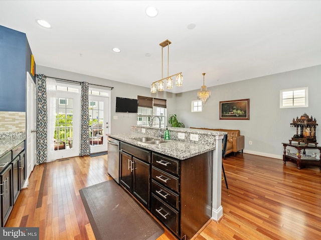 12404 Carriage Park Pl, Clarksburg, MD 20871 - kitchen featuring stainless steel dishwasher, light wood finished floors, a breakfast bar area, pendant lighting, and dark brown cabinets