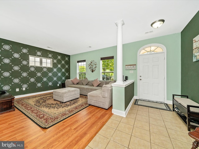 12404 Carriage Park Pl, Clarksburg, MD 20871 - living room with decorative columns, wallpapered walls, an accent wall, and light wood-type flooring